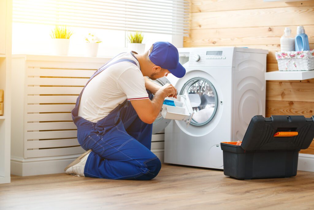 un hombre reparando la lavadora